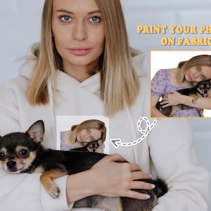 May include: A black and brown Chihuahua dog is held in a person's arms, wearing a white hoodie. The image includes a smaller image of the dog and person, with the text "PRINT YOUR PHOTOS ON FABRIC".