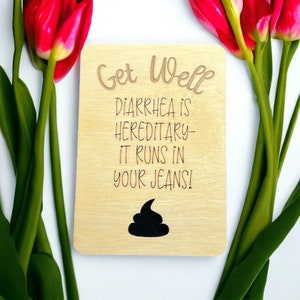 May include: A wooden card with the text "Get Well" and a humorous message about diarrhoea. The card features a cartoon poop emoji.