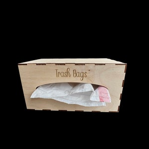 May include: A wooden box with a slot for trash bags. The box is labeled "Trash Bags".