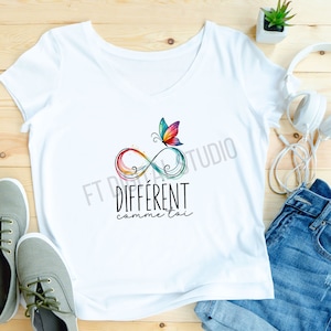 Pode incluir: Camiseta branca com um símbolo de infinito arco-íris e uma borboleta. O texto "DIFFERENT comme toi" está impresso abaixo do símbolo.