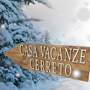 May include: A wooden arrow sign with the text "CASA VACANZE CERRETO" in white lettering. The sign is pointing to the right and is set against a snowy background with a path leading into the distance.