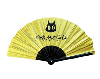 以下が含まれることがあります： 黒い猫の顔と「Party Must Go On」という文字が書かれた黄色の扇子です。
