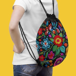 May include: A black drawstring backpack with a colorful floral embroidery pattern. The flowers are red, yellow, blue, pink, and green. The backpack has black drawstrings.