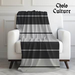 May include: A black and gray striped throw blanket with the text "Cholo Culture" in black lettering.