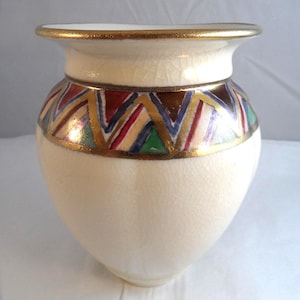 May include: Cream ceramic vase with a gold rim and a band of colourful geometric patterns. The vase has a wide mouth and a rounded body, showcasing a vintage aesthetic.