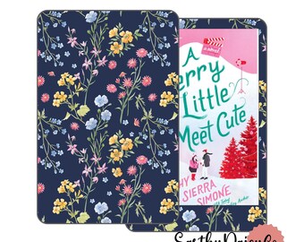 May include: A navy blue e-reader cover with a floral pattern of yellow, pink, and blue flowers. The cover is open, revealing a book titled "A Merry Little Meet Cute" with a winter scene illustration. The brand name "EarthyDaisyCo" is at the bottom.