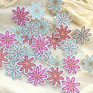 Peut inclure: Plusieurs autocollants de fleurs color&eacute;es dans des tons de rose, corail et turquoise avec des bordures blanches. Les autocollants sont dispos&eacute;s sur une surface textur&eacute;e de couleur cr&egrave;me, cr&eacute;ant un affichage joyeux et artistique. Les p&eacute;tales de fleurs ont un design superpos&eacute;.