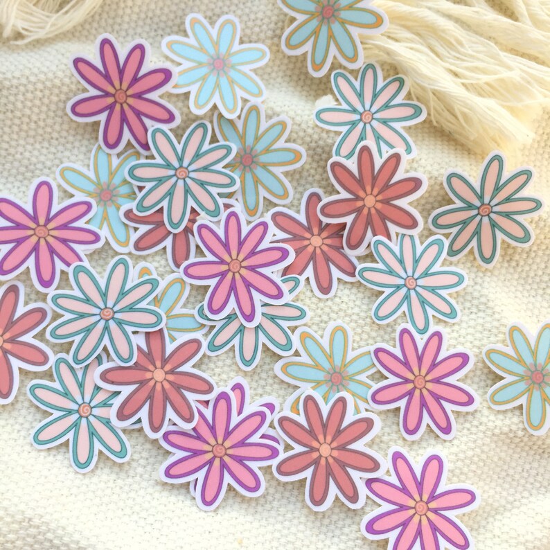 Peut inclure: Plusieurs autocollants de fleurs color&eacute;es dans des tons de rose, corail et turquoise avec des bordures blanches. Les autocollants sont dispos&eacute;s sur une surface textur&eacute;e de couleur cr&egrave;me, cr&eacute;ant un affichage joyeux et artistique. Les p&eacute;tales de fleurs ont un design superpos&eacute;.