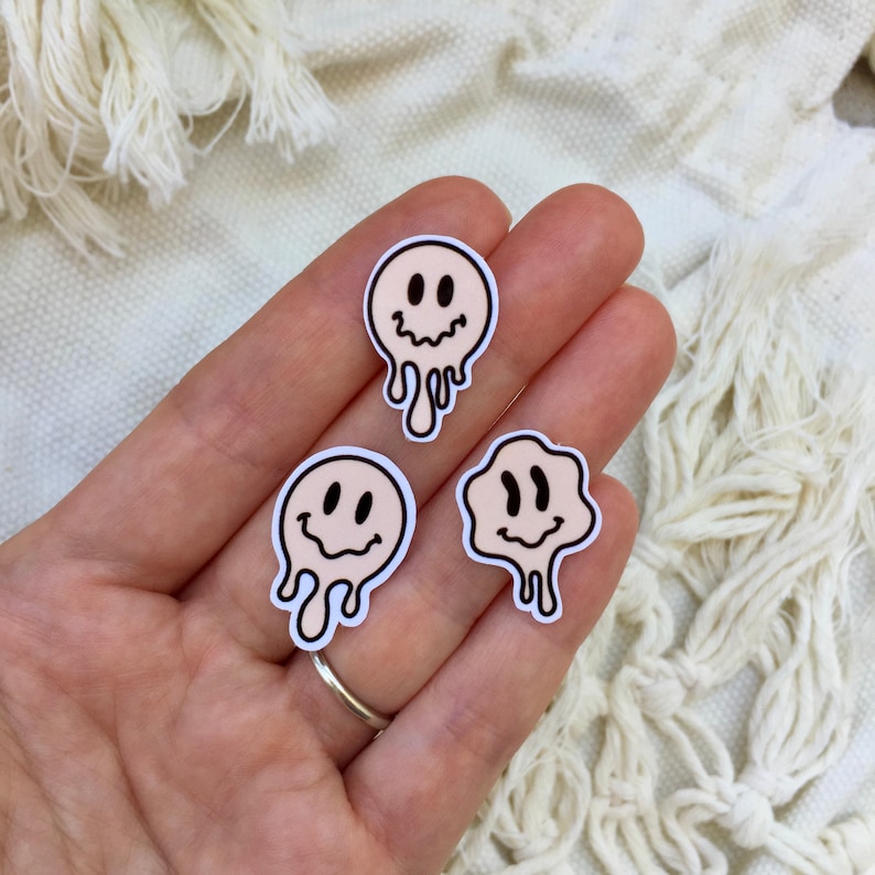 Puede incluir: Tres pegatinas de cara sonriente beige con contornos negros. Las caras sonrientes est&aacute;n goteando, dando la impresi&oacute;n de que se est&aacute;n derritiendo.