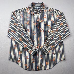 May include: A long-sleeve button-down shirt featuring a pattern of vertical navy blue and cream stripes overlaid with a print of scattered autumn leaves in shades of orange, yellow, and brown. The shirt includes a collar and a single chest pocket.