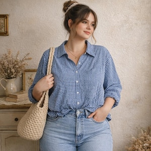 Könnte beinhalten: Eine Frau in einem blau-weiß karierten Hemd und hellblauen Jeans, die eine beige gehäkelte Tragetasche trägt. Sie hat ihr Haar zu einem Dutt gebunden und trägt eine Halskette. Das Hemd ist zugeknöpft.