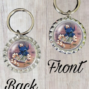 May include: A blue Stitch keychain with a silver metal cap. Stitch is reading a book to a group of baby ducks. The back of the keychain is blank.