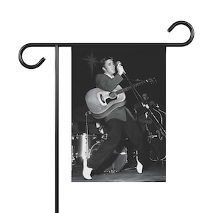 Elvis Presley. Elvis Presley in concert dancing with his guitar in black and white Garden & House Banner or flag.