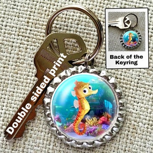 May include: A silver bottle cap keychain with a colorful image of a cartoon seahorse in an underwater scene. The keychain is attached to a silver key ring and a silver key. The text "Double sided print" is printed on the key. The back of the keychain is shown in a smaller image.