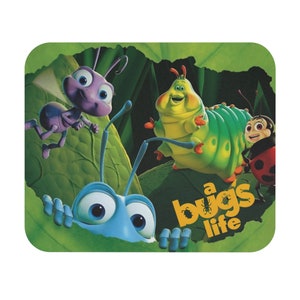 May include: A Bugs Life mousepad featuring cartoon characters. The design includes a blue bug peeking out from a green leaf, an ant, a caterpillar, and a ladybug. The words "a bug's life" are printed in yellow.