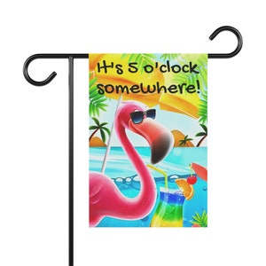 May include: A pink flamingo with sunglasses and a tropical drink in a blue glass with a cherry and orange slice. The flamingo is in front of a beach scene with palm trees and a yellow umbrella. The text "It's 5 o'clock somewhere!" is written in black on a yellow background.