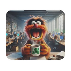 May include: A cartoon character with orange fur and a big mouth holding a white coffee mug with the text "I NEED COFFEE!" in green letters. The character is sitting at a desk in an office setting.