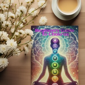May include: A book titled "Beginner's Guide to Chakras" with a colorful illustration of a person in a meditative pose with seven chakras represented by swirling circles of different colors. The author's name, Crystal Johns, is printed at the bottom of the cover.
