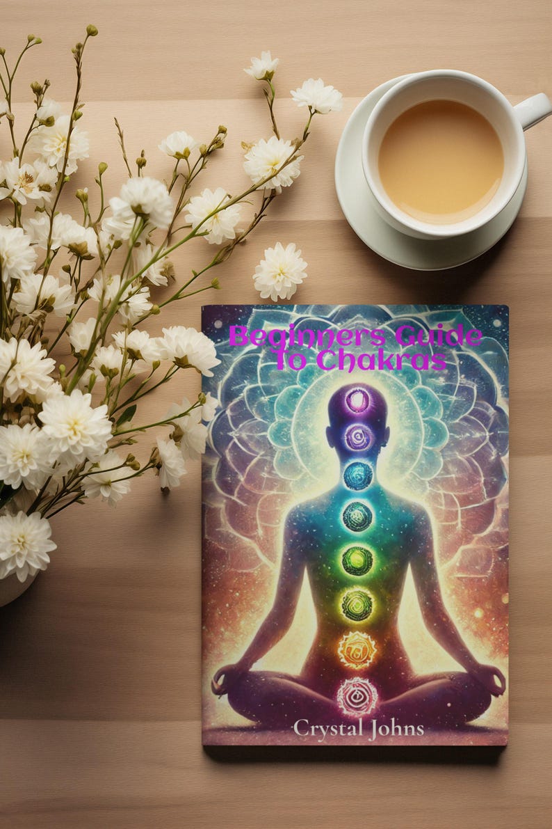 May include: A book titled "Beginner's Guide to Chakras" with a colorful illustration of a person in a meditative pose with seven chakras represented by swirling circles of different colors. The author's name, Crystal Johns, is printed at the bottom of the cover.