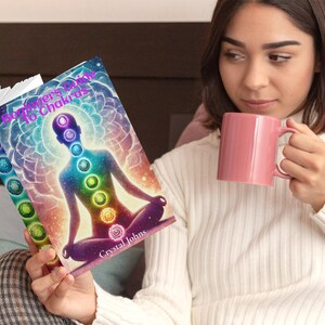 May include: A book titled "Beginner's Guide to Chakras" with a colorful cover featuring a person meditating with a rainbow aura. The book cover has a vibrant, abstract design with a person sitting in a lotus position.