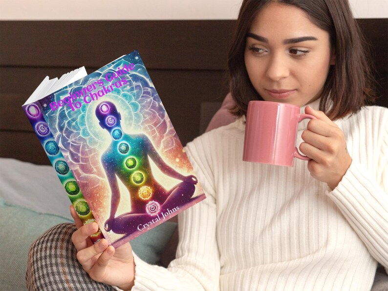 May include: A book titled "Beginner's Guide to Chakras" with a colorful cover featuring a person meditating with a rainbow aura. The book cover has a vibrant, abstract design with a person sitting in a lotus position.