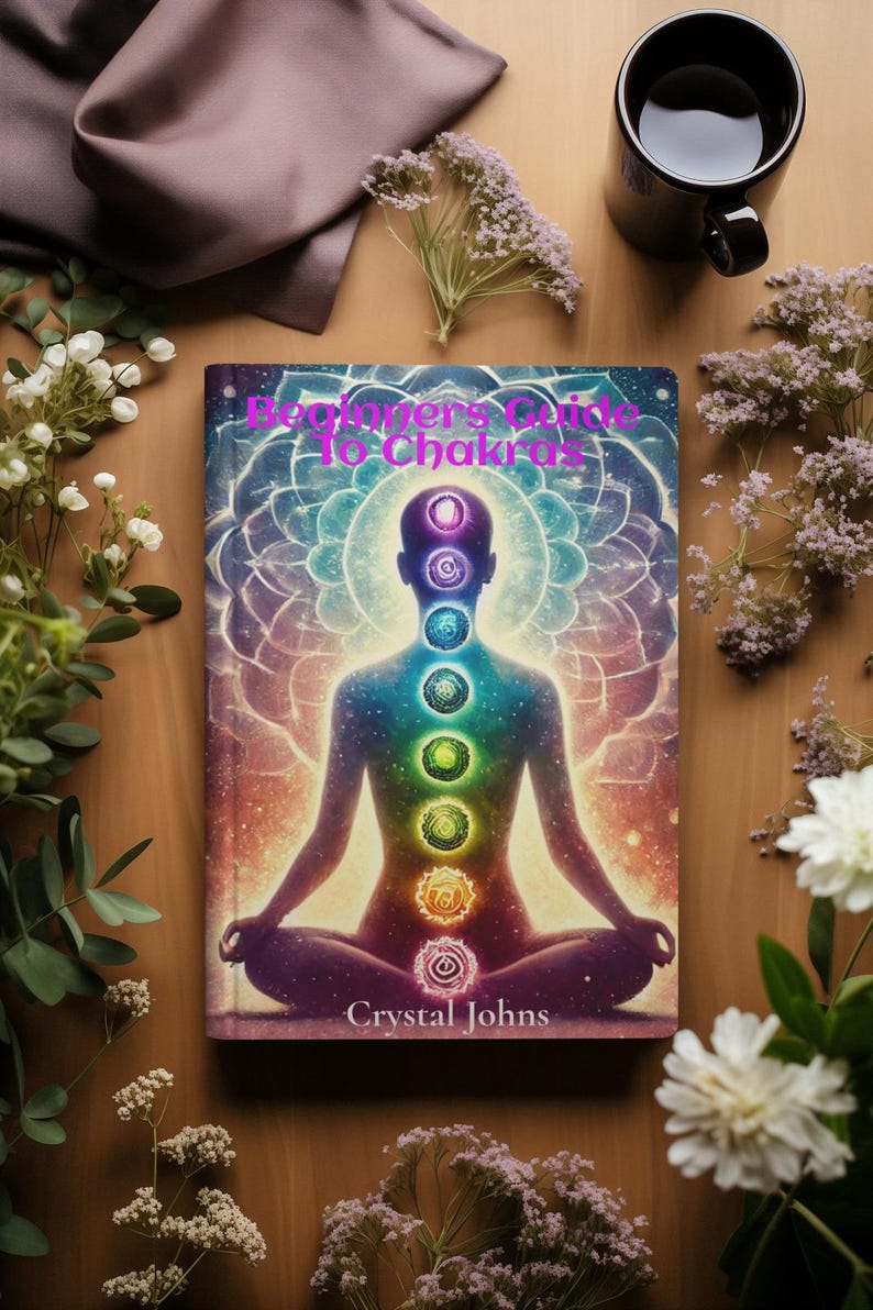 May include: A book titled "Beginner's Guide to Chakras" with a colorful illustration of a person in a meditative pose with seven chakras represented by colored circles along the spine. The author's name, Crystal Johns, is printed at the bottom of the cover.
