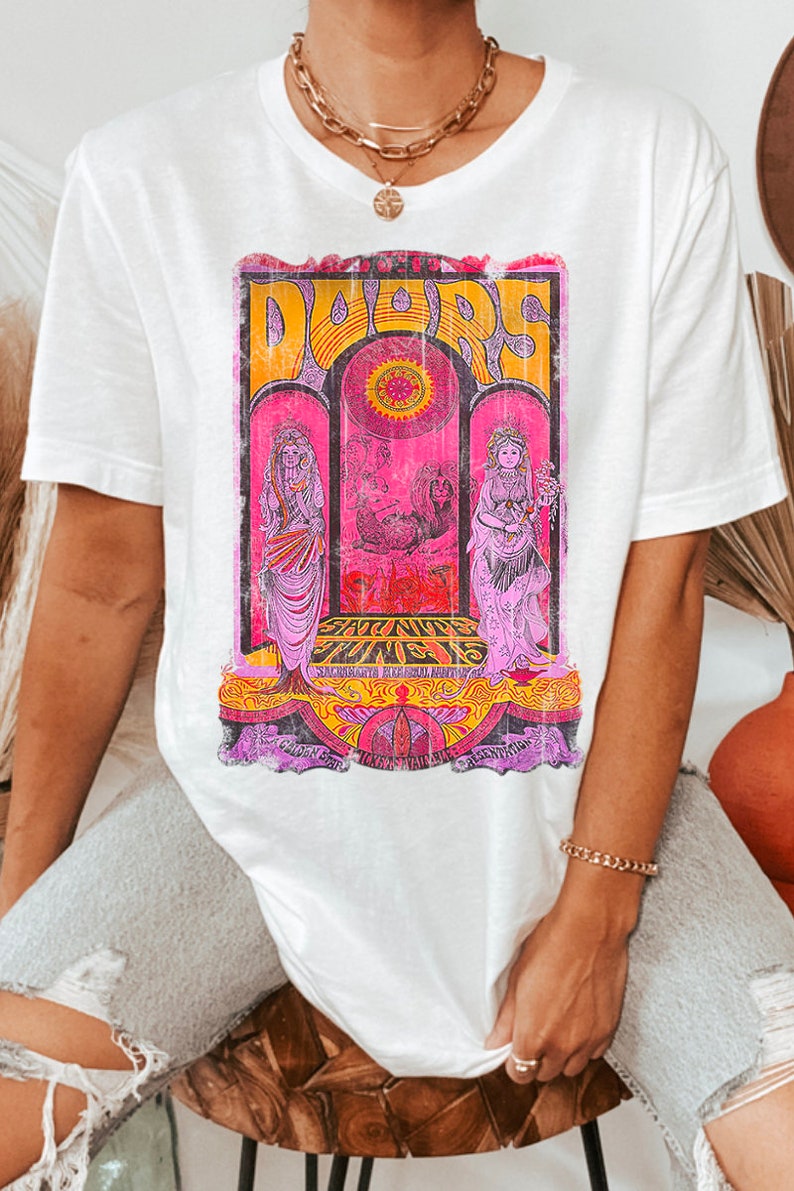 May include: White t-shirt with a vintage graphic print of a band called "Doors" with the text "Sat. Nite June 15" and other details. The graphic is in pink, yellow, and orange.