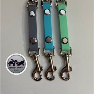 Könnte beinhalten: Drei Hunde-Leinenbefestigungen mit silbernen Drehclips. Die Leinen sind aus Leder und in Grau, Türkis und Hellgrün erhältlich.
