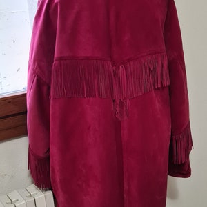 May include: A burgundy suede jacket with fringe detailing on the back and sleeves. The jacket has a fur collar.
