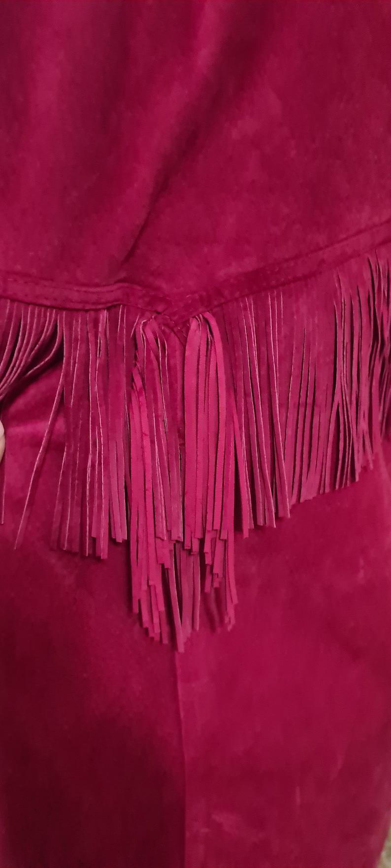 May include: A magenta suede skirt with a fringe trim.
