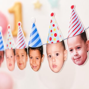 May include: A party banner featuring a series of cutouts of children's faces, each wearing a colourful paper party hat. The hats display various patterns including red and blue stripes, blue diagonal stripes, and red dots with yellow stars.