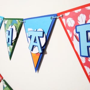 May include: A blue and red banner with the word "Happy" spelled out in blue letters. Each letter is on a separate triangular flag. The flags are decorated with tropical patterns.