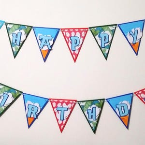 May include: A blue and green birthday banner with the words "Happy Birthday" in white letters. The banner features a cartoon character with blue fur and large ears.