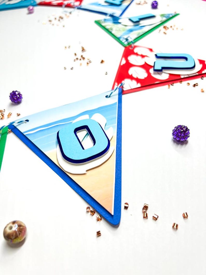 May include: A blue and white beach-themed banner with the number "0" in blue on a white background. The banner is made of paper and has a scalloped edge. The number is raised and has a white outline.