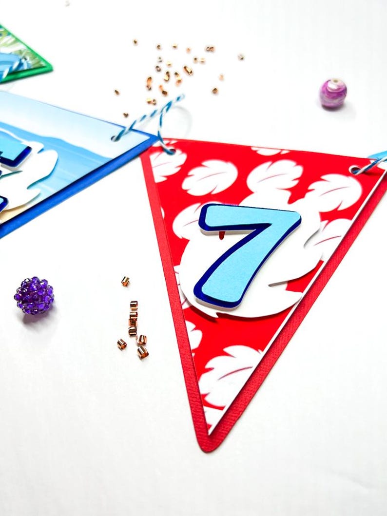 May include: A red triangular banner with a white floral pattern and a blue number 7. The banner is decorated with white and blue paper.