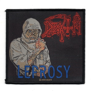 Może przedstawiać: Naszywka haftowana w kolorze czarnym i białym z postacią w kapturze w środku. Postać ma na sobie białą szatę i ma czaszkę na twarzy. Tekst "DEATH" jest czerwony, a tekst "LEPROSY" jest niebieski. Tekst "© 2003 DEATH" jest biały na dole.