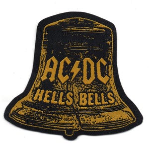 May include: A black and gold embroidered patch shaped like a bell with the text "AC/DC" and "HELLS BELLS" on it.