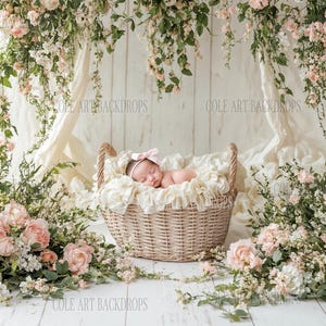 May include: A newborn baby girl sleeping in a wicker basket surrounded by pink and white flowers. The basket is lined with a white fabric and the baby is wearing a pink headband.
