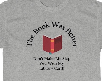 Pode incluir: Camiseta cinza com um gráfico de livro e o texto "The Book Was Better" e "Don't Make Me Slap You With My Library Card!"