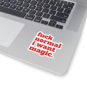 Puede incluir: Una pegatina blanca con el texto "fuck normal i want magic" en rojo, con fuente sans-serif. La pegatina está sobre un portátil plateado, con el teclado visible.