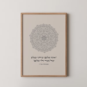 May include: A framed print featuring a beige background with a black mandala design. The print includes Hebrew text in black. The frame is made of light brown wood.
