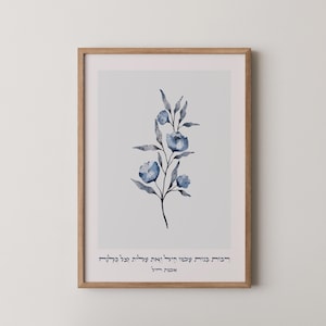 Può includere: Una stampa incorniciata con un'illustrazione ad acquerello di fiori e foglie blu su sfondo bianco. L'opera d'arte è in una cornice di legno marrone chiaro. Il testo in ebraico è nella parte inferiore della stampa.