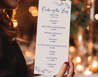 May include: A white card with blue text outlining the order of the day for a wedding. The card lists the ceremony, reception, wedding breakfast, speeches, cutting the cake and first dance, supper, last orders, and carriages. The date of the wedding is listed as 15/05/24.