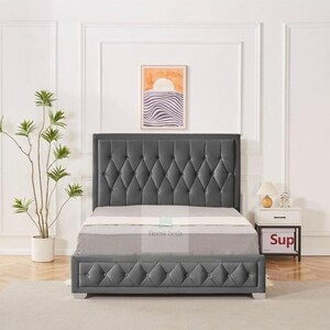 May include: A grey upholstered bed frame with a diamond tufted headboard and footboard. The bed frame has a white mattress and a white bedside table with a lamp and a small box that says "Sup".