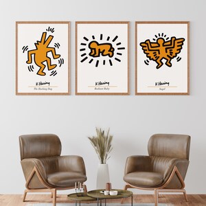 May include: Three framed prints of Keith Haring artwork. The prints are in a minimalist style with white backgrounds and black outlines. The artwork features a barking dog, a radiant baby, and an angel. The prints are labeled with the artist's name and the title of each piece.