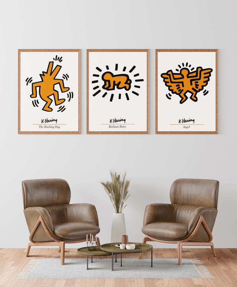 May include: Three framed prints of Keith Haring artwork. The prints are in a minimalist style with white backgrounds and black outlines. The artwork features a barking dog, a radiant baby, and an angel. The prints are labeled with the artist's name and the title of each piece.