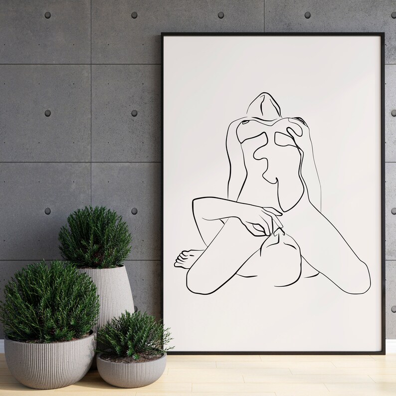 Peut inclure: Un dessin au trait noir et blanc de deux figures dans une &eacute;treinte amoureuse. Le dessin est encadr&eacute; et accroch&eacute; &agrave; un mur gris.
