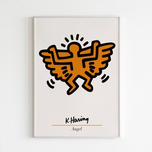 May include: A framed print of a stylized orange figure with wings, by artist Keith Haring. The print is titled "Angel" and is on a beige background.