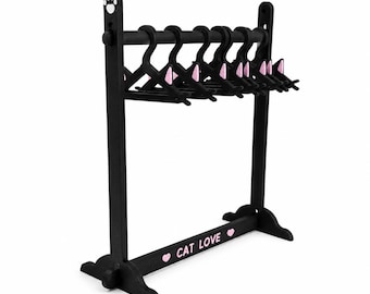 May include: A black clothing rack with a horizontal bar holding several small black hangers. The frame features a white paw print at the top and the text CAT LOVE in pink with two pink hearts on the base. The hangers have small pink cat ears.