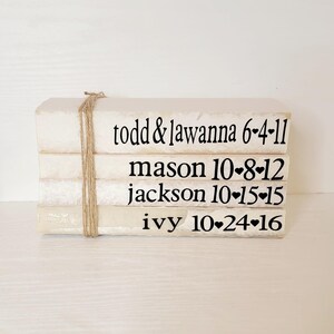 May include: A stack of white books with black text. The books are tied together with twine. The text on the books reads: "todd & lawanna 6-4-11", "mason 10-8-12", "jackson 10-15-15", and "ivy 10-24-16".